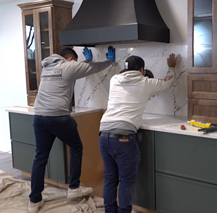 Two Installers pushing the tile backsplash into place.